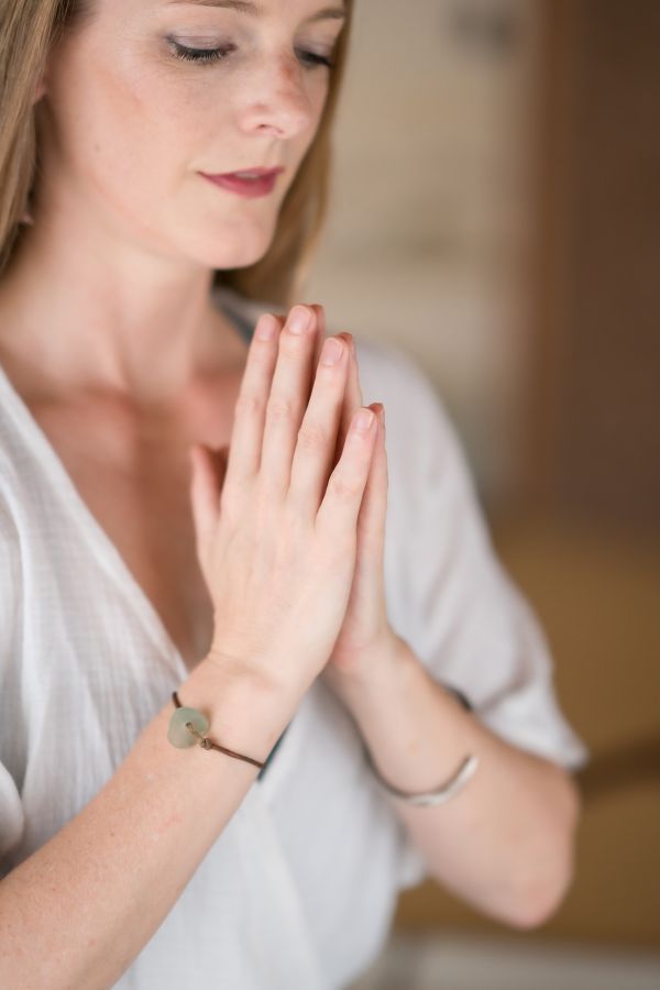 Yoga starter kit prayer hands A young woman is sitting with her hands in prayer position - a beginner yoga pose.
