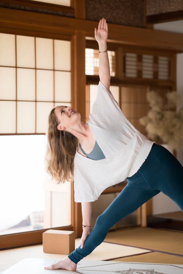 Yoga starter kit triangle pose A young woman holds a yoga pose while smiling.